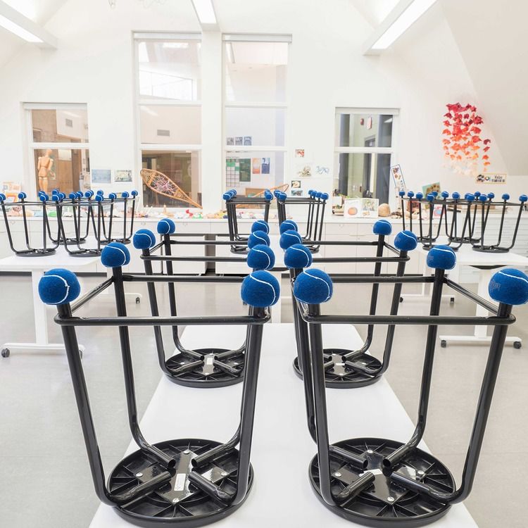 Classroom with stools upside down on desks showing hushh-ups on each stool foot