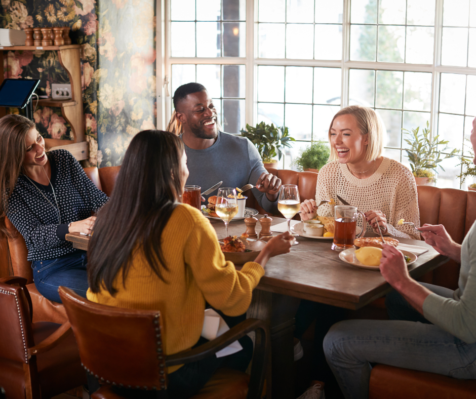 a group of people sitting at a table laughing and conversing in a restaurant