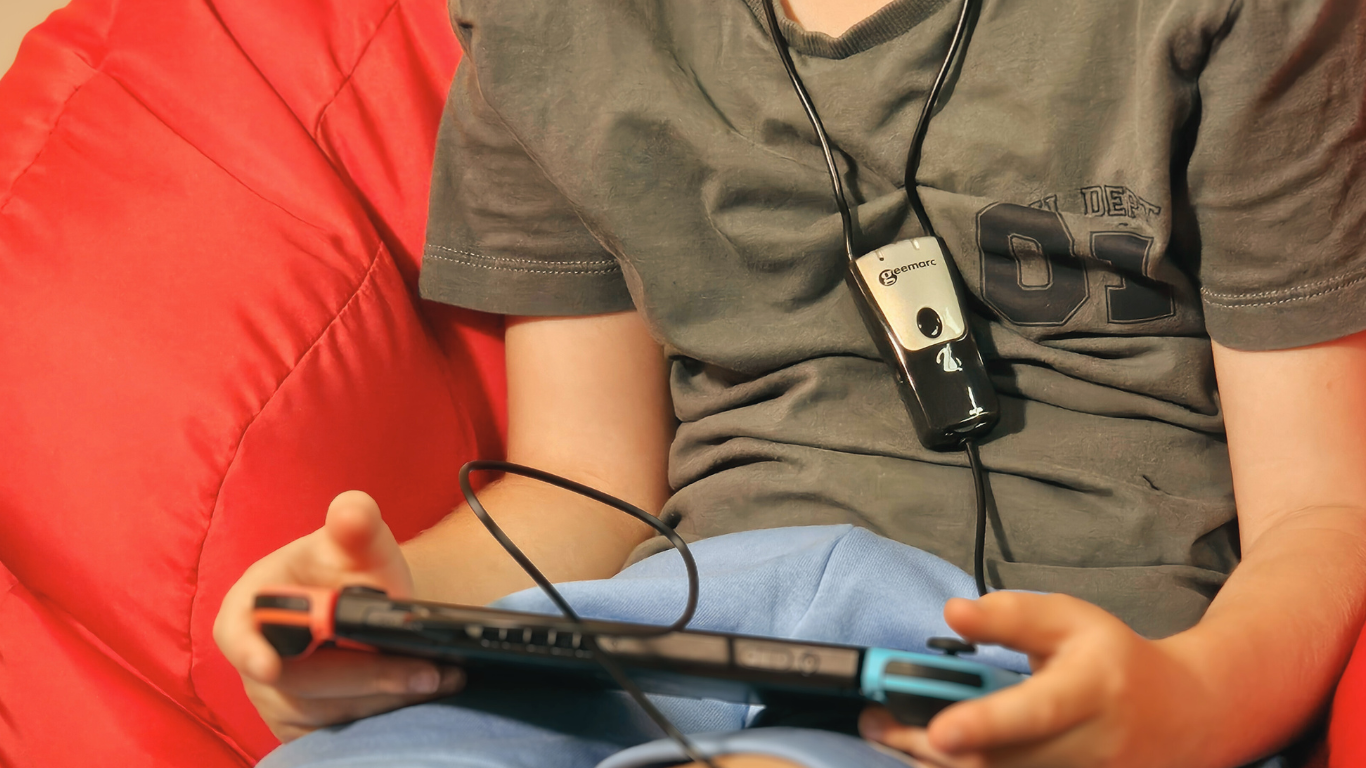 Child wearing Geemarc neckloop while playing a Nintendo switch games console