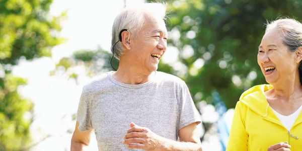 Man wearing ear gear on his hearing aid while running with a partner