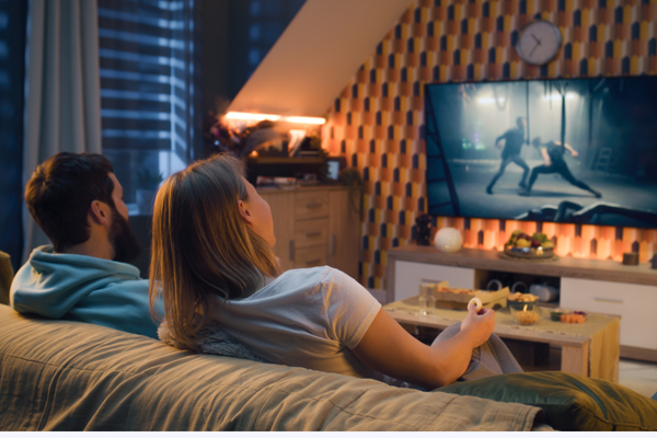 Couple enjoying watching the TV while sat on a sofa in their home